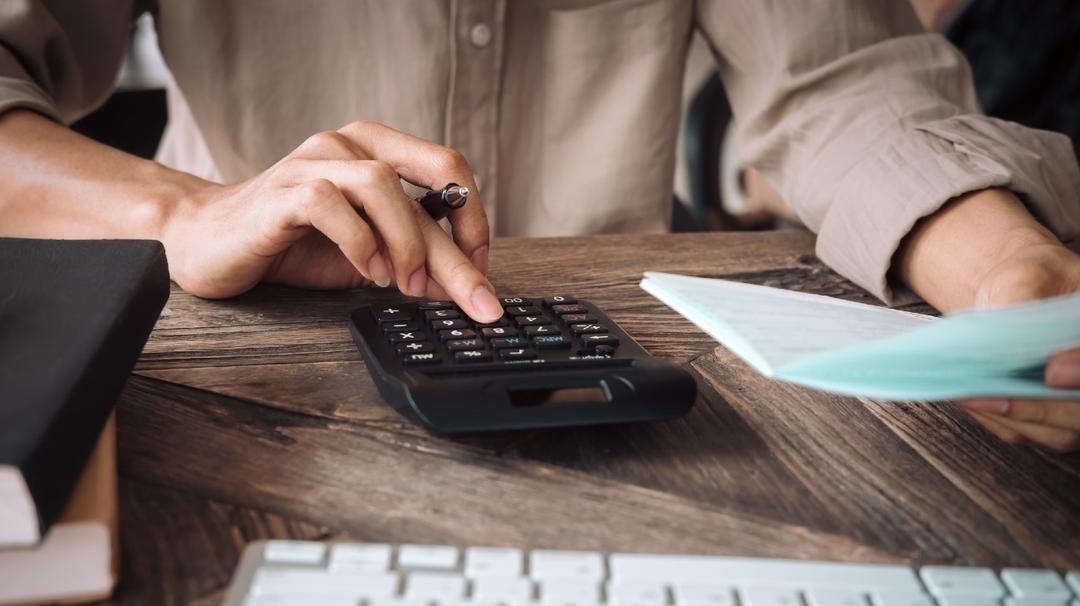 Person using calculator to compare difference between tax deduction and tax credit