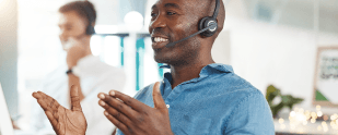 A man in a headset is talking to a customer in a call center.