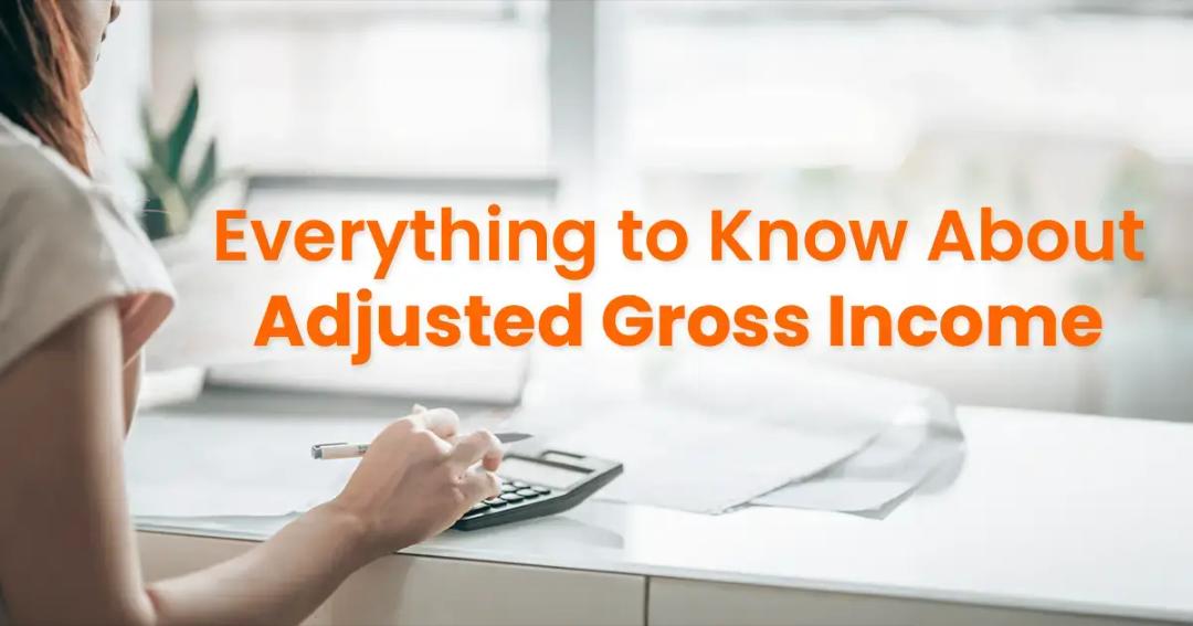 Woman seated at a desk calculating finances with a calculator, with the text "everything to know about adjusted gross income" overlaying the image.