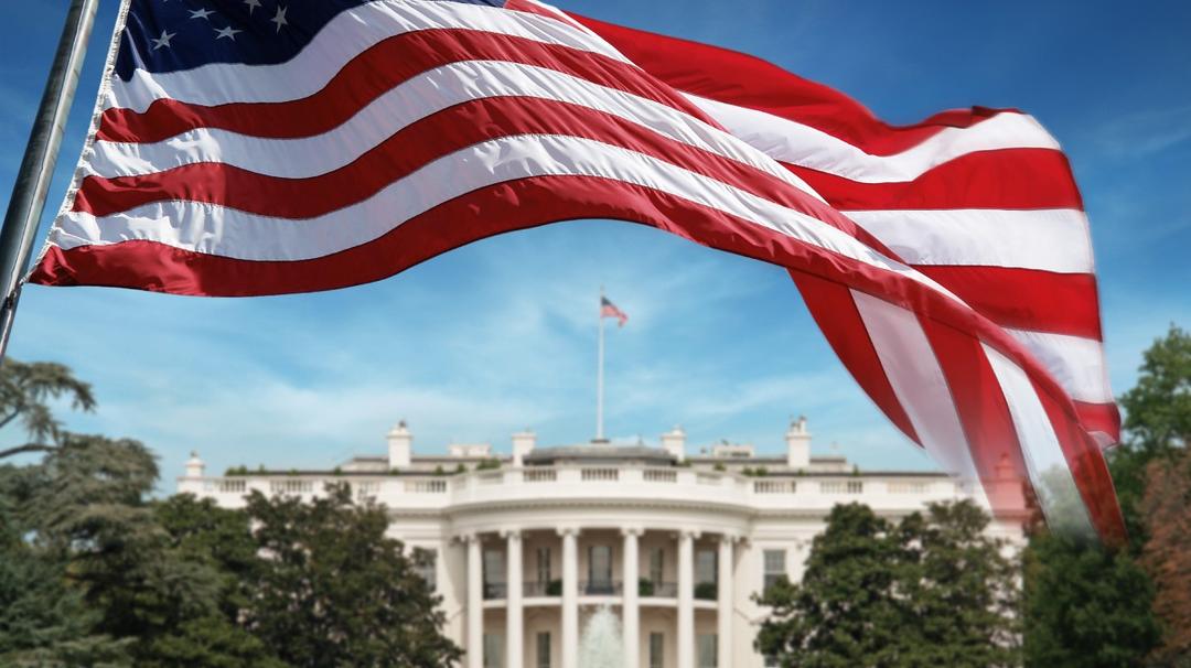 American Flag in front of The White House in Washington D.C. Background out of focus.