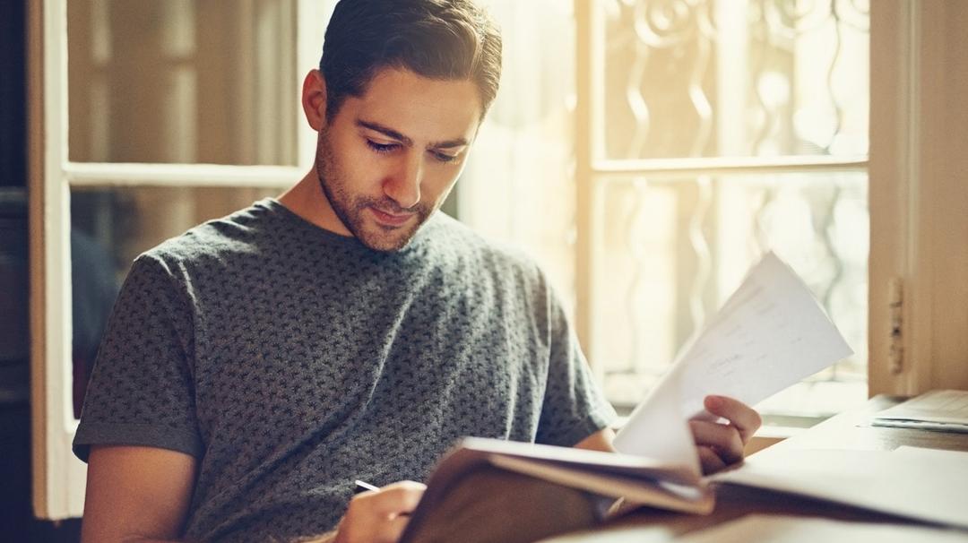 Man in a home office reading about the Express Bridge Loan Pilot Program in a book.