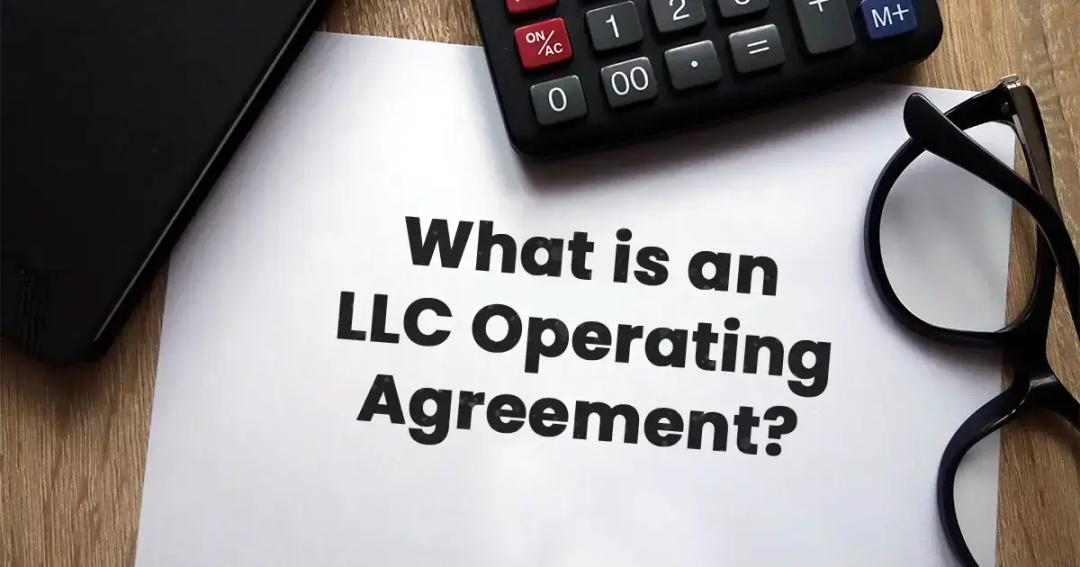 Paper titled "what is an llc operating agreement?" beside glasses and a calculator on a wooden table.